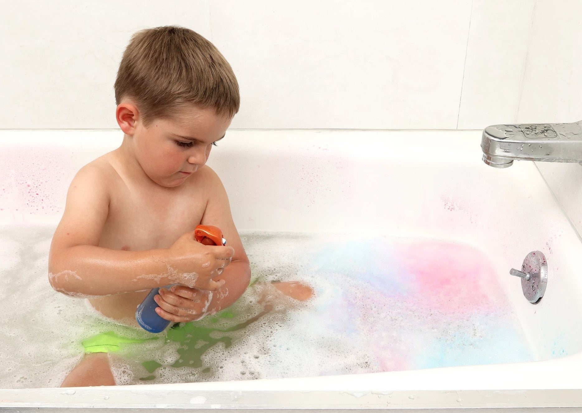 Child spraying bottle in bathtub playing with Bath Tub Fun Messy Play Kit