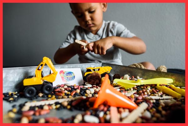 Toddler plays with a construction-themed sensory bin - Messy Play - how to teach a child responsibility