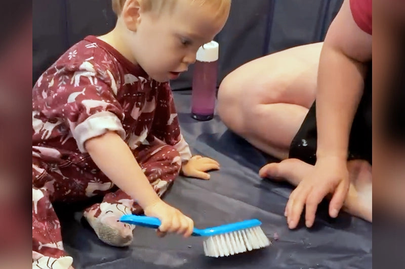 Toddler plays with a construction-themed sensory bin - Messy Play - how to teach a child responsibility