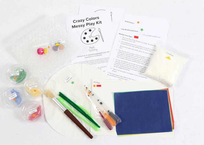 Materials and contents of the Crazy Colors Messy Play Kit, including instructions, art paper, liquid water colors, powdered color, pipe cleaners, paintbrush, cornstarch, and color tablets.