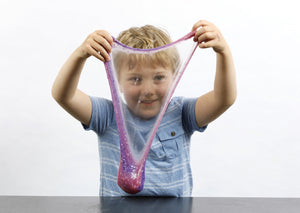 Young boy stretching purple and pink color-changing Rockstar slime in front of his face.