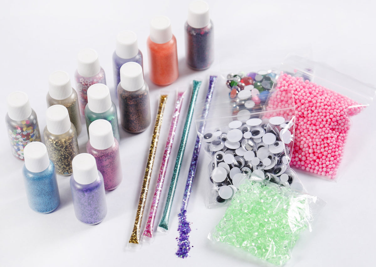 Mix-ins for slime making, including vials of glitter, tubes of glitter, beads, google eyes, and jewels.