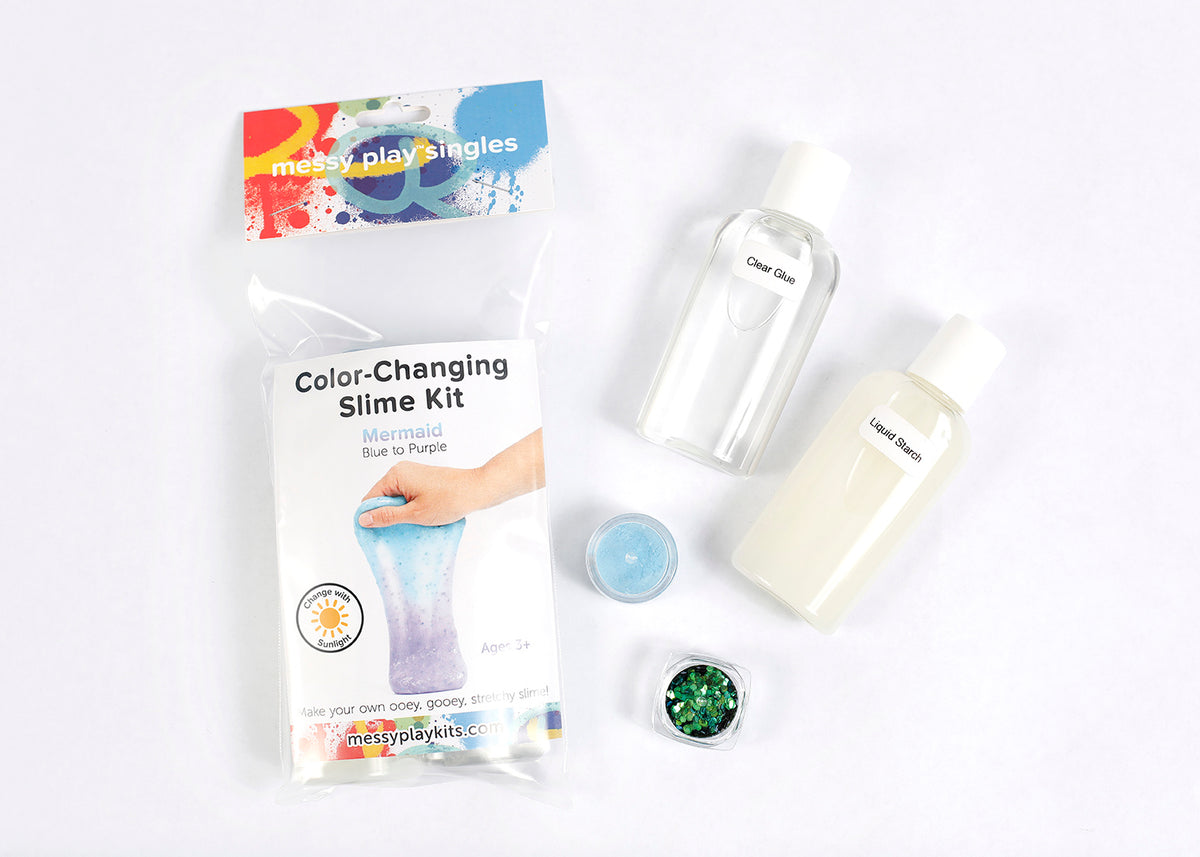 Packaging and contents of a Mermaid slime kit, including a glue bottle, liquid starch bottle, glitter, and color-changing pigment that changes the slime from blue to purple in the sunlight