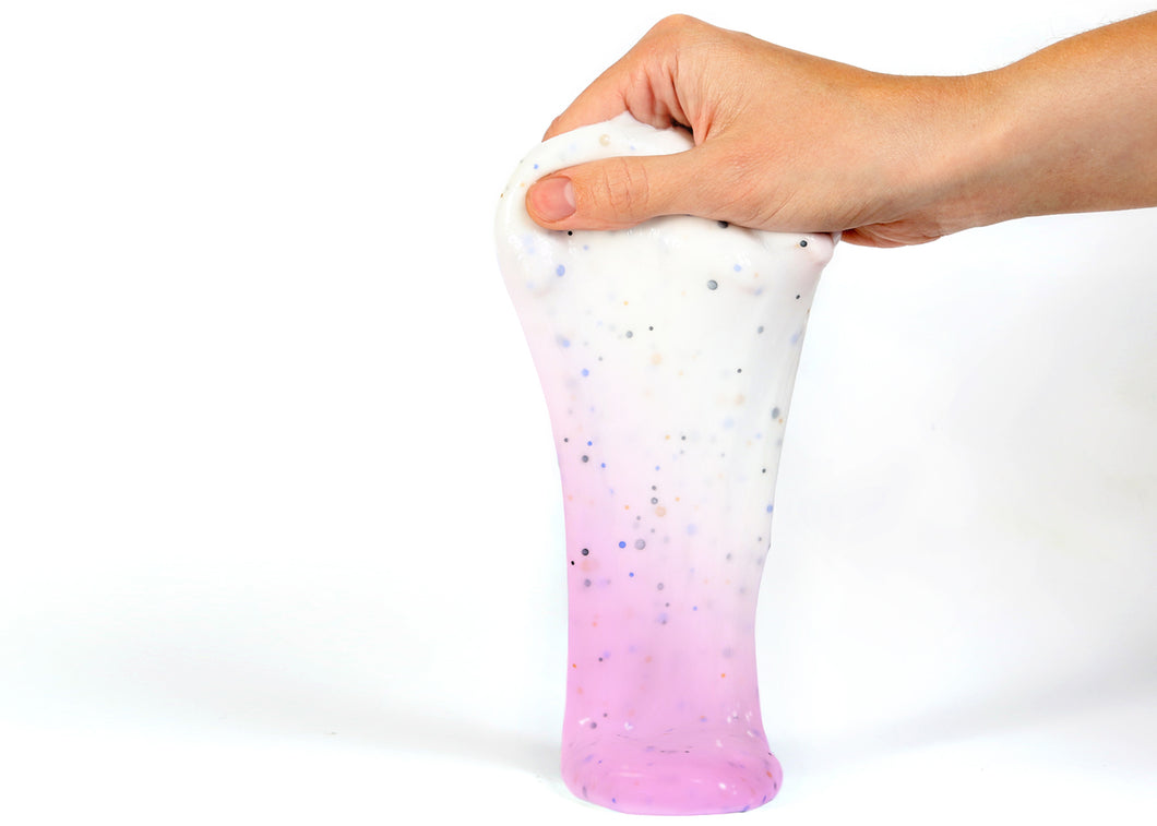 Hand holding Messy Play Kit's color-changing Unicorn slime that changes from white to pink in the sunlight