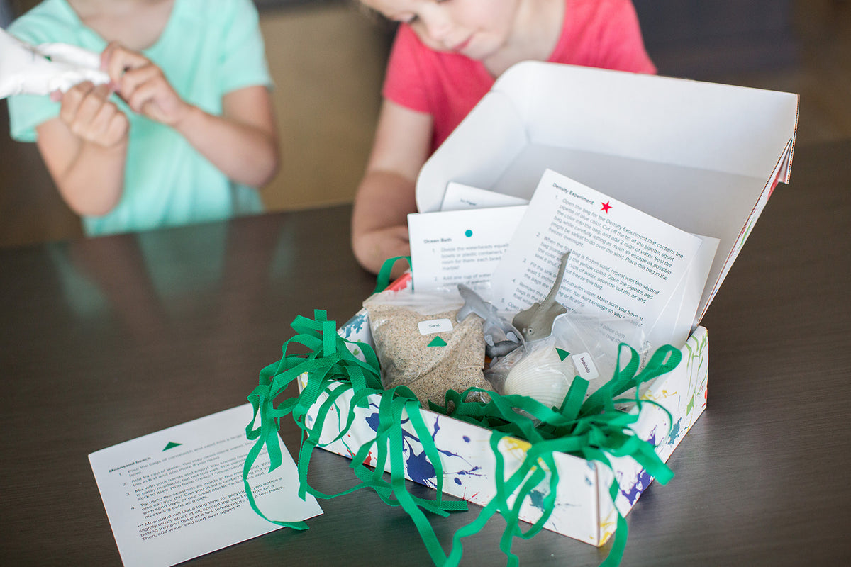 An open STEM subscription box showing contents including density experiment for kids