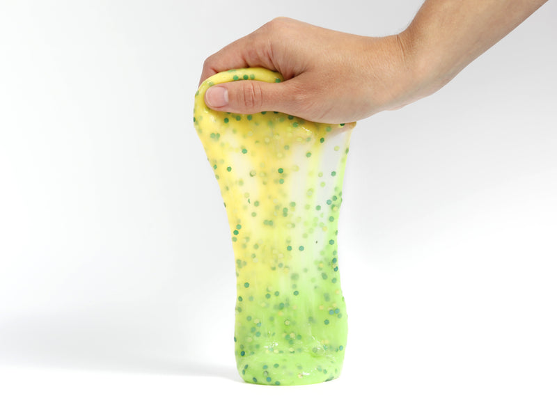 Hand holding Messy Play Kit's Dragon slime that changes from yellow to green in the sunlight 