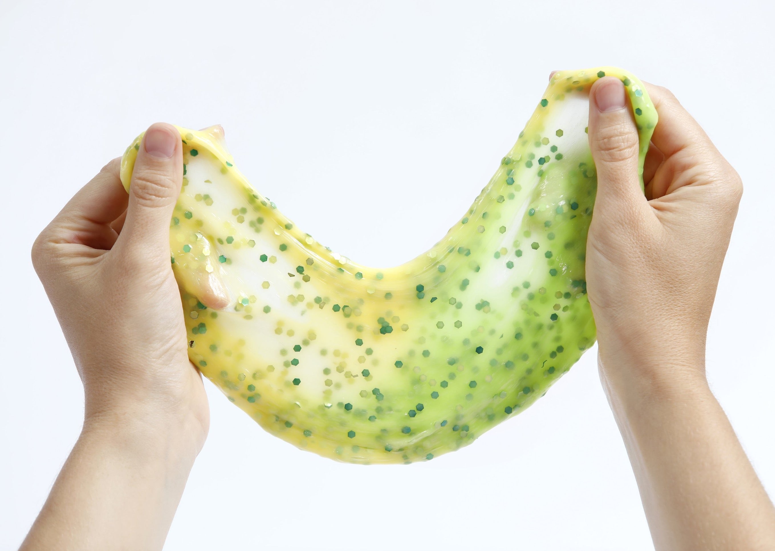 Two hands stretching Messy Play Kit's Dragon slime that changes from yellow to green in the sunlight