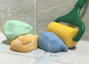 Playdough soap in three colors, green, yellow, and blue. Pictured with a play dough roller tool.
