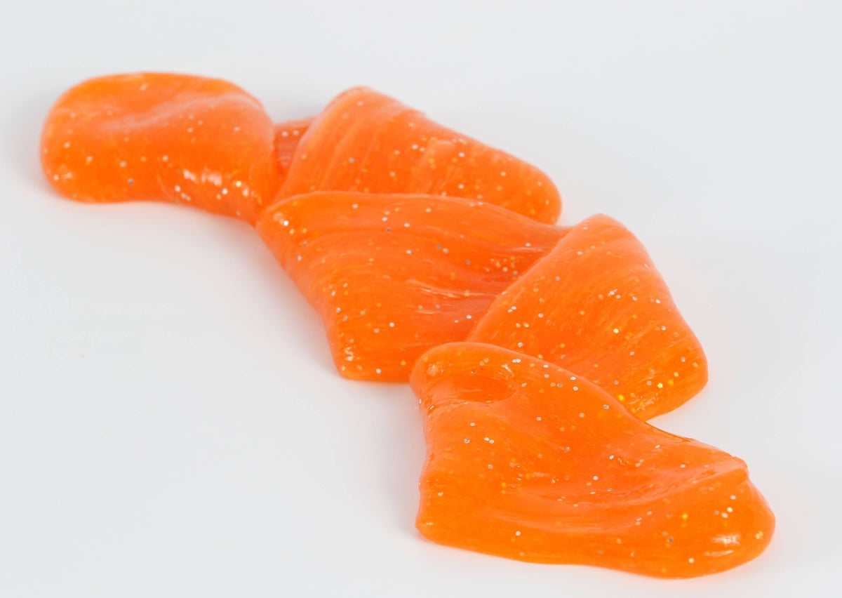 Stretched and folded orange glitter slime by Messy Play Kits.