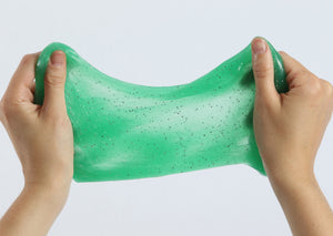 Two hands pulling and stretching the green glitter slime by Messy Play Kits.