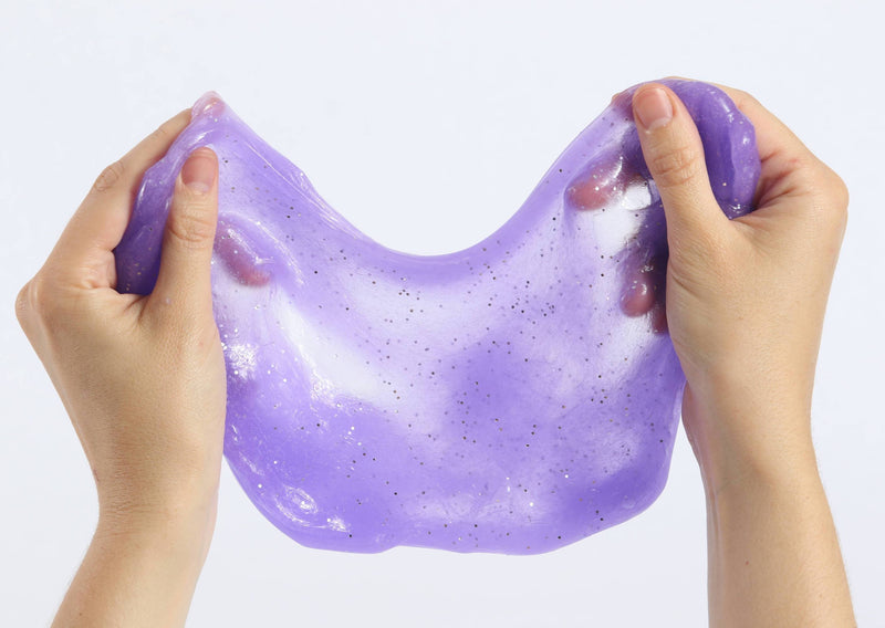 Two hands pulling and stretching the purple glitter slime by Messy Play Kits.