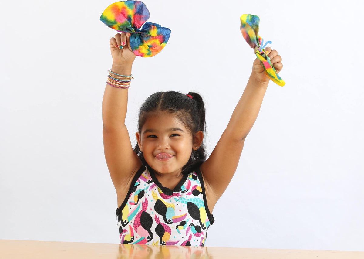 Girl proudly holding up tie dyed butterfly crafts.
