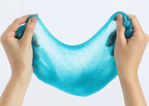 Two hands pulling and stretching the turquoise glitter slime by Messy Play Kits.