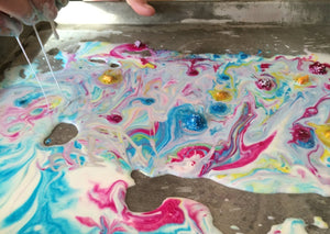 Close up of colorburst oobleck in a pan, liquid ooze with colors streaked through it.