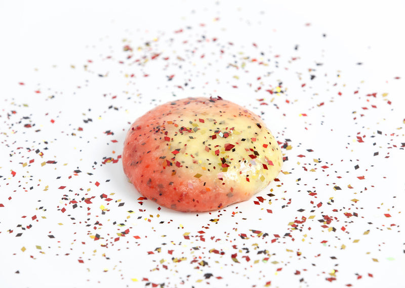 Glitter surrounding a round ball of Phoenix slime that changes from yellow to red in the sunlight 